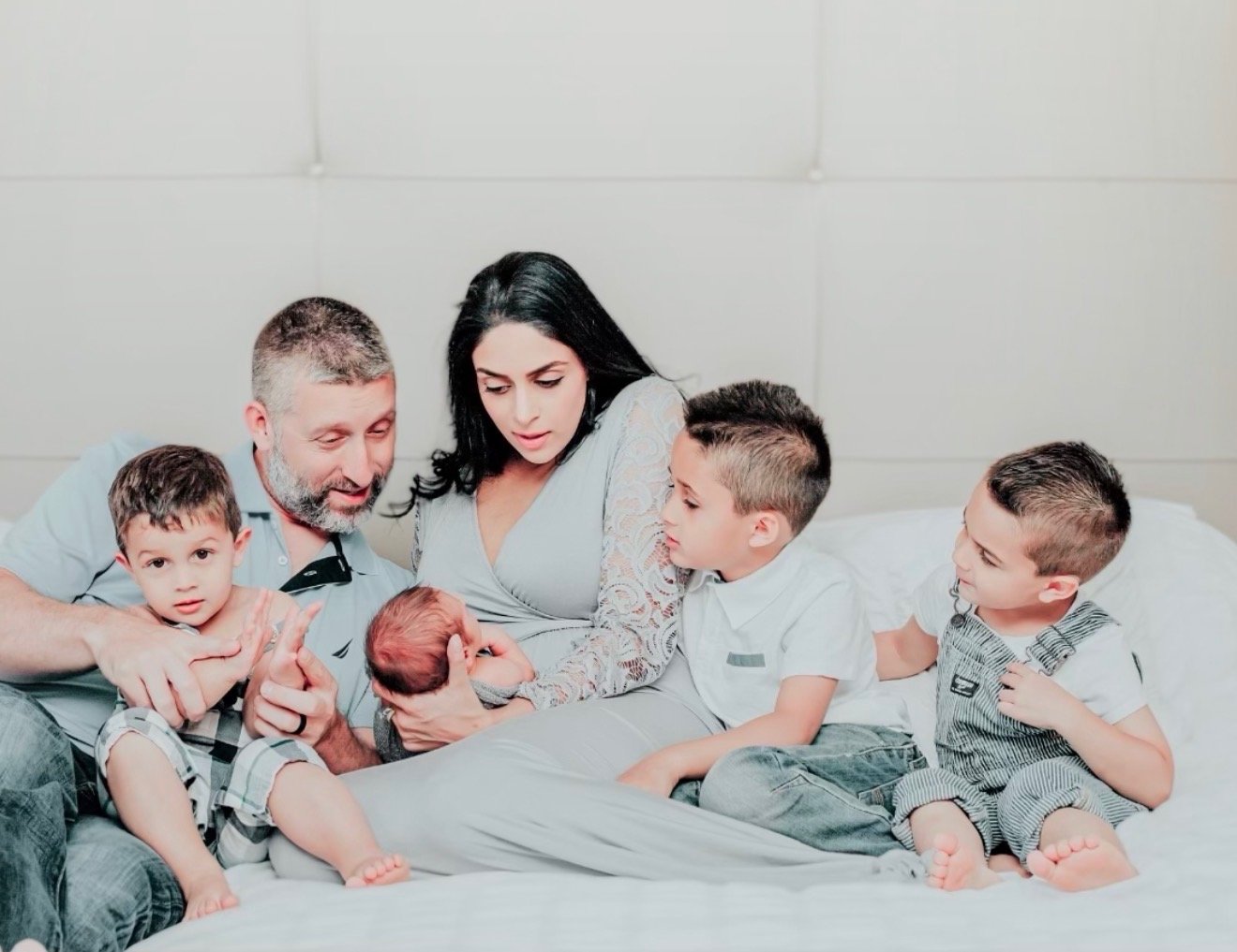 Sadia with her husband and their four boys, cradling their newborn son